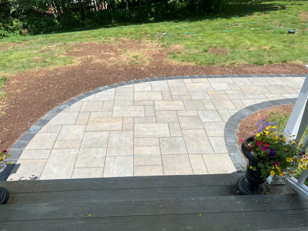 Large-format paver patio with a dark border and curved edge