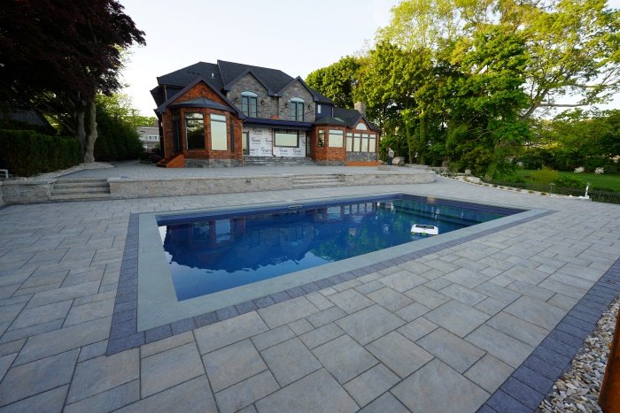In-ground pool surrounded by a light gray paver pool deck