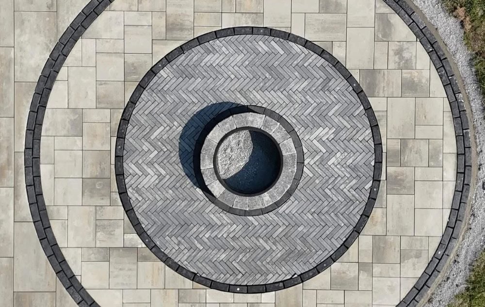 Overhead view of a circular fire pit patio with inlaid border rings in Wolcott, CT