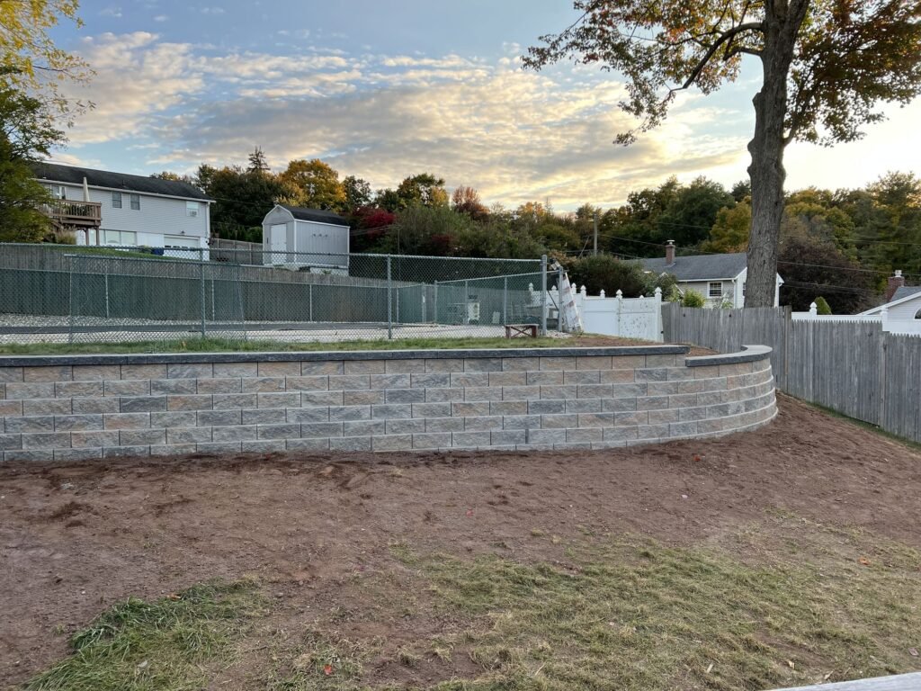 Curved block retaining wall around a raised backyard in Waterbury, CT