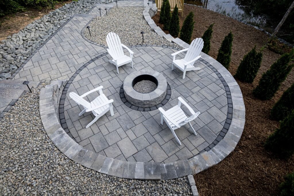 Round fire pit patio with Adirondack chairs and a gravel surround