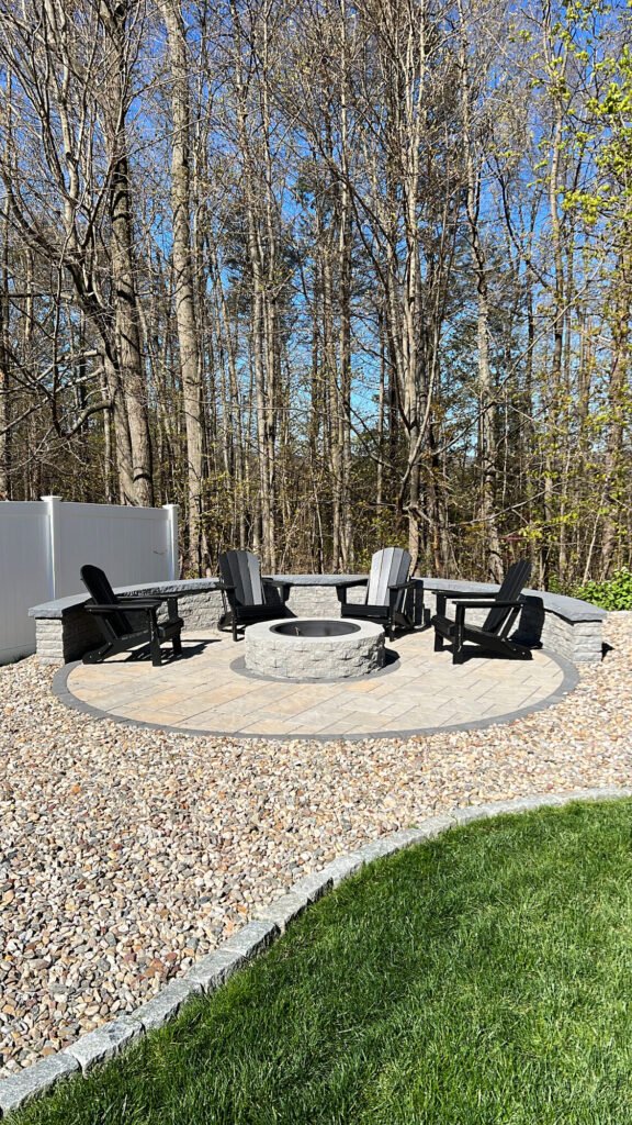 Round paver fire pit patio with Adirondack chairs and a gravel border