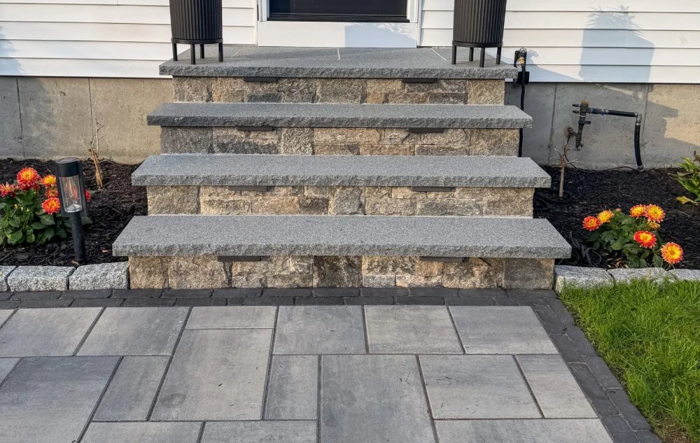 Front entry steps with stone treads and stone veneer risers above a paver landing