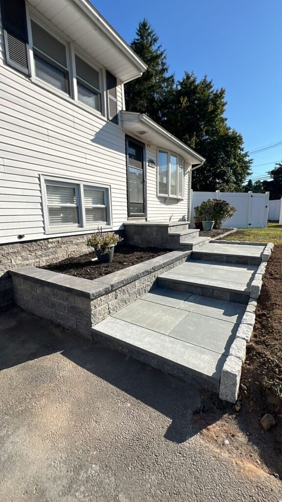 Bluestone front steps with retaining walls and a granite-edged walkway