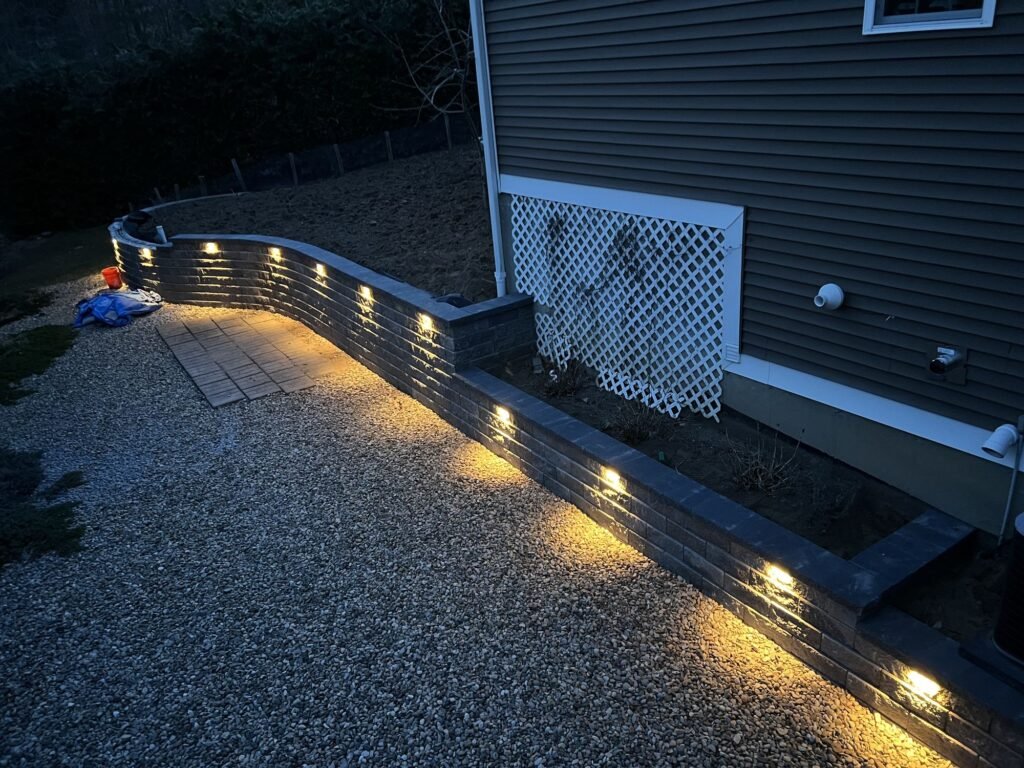 Low-voltage lights under retaining wall caps at dusk in Southington, CT