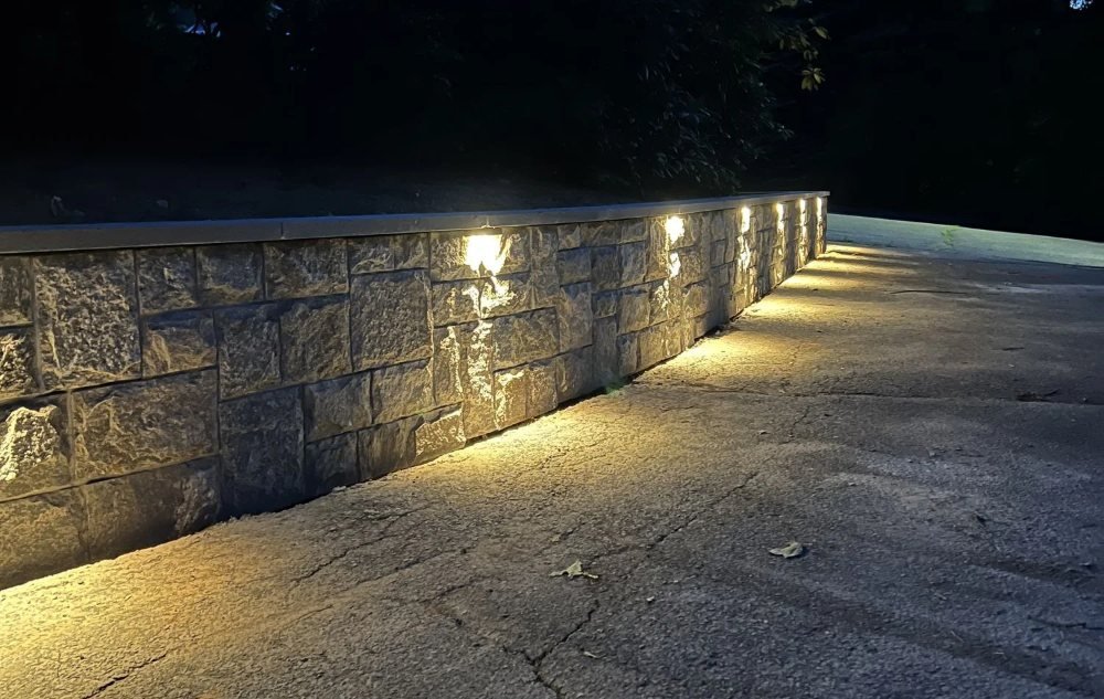 Lit stone-faced driveway wall at dusk in Southington, CT