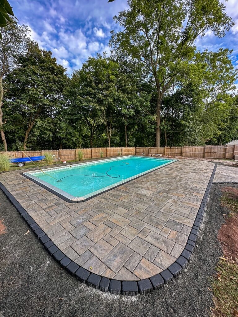 Paver pool deck with a rounded end and dark border in North Haven, CT