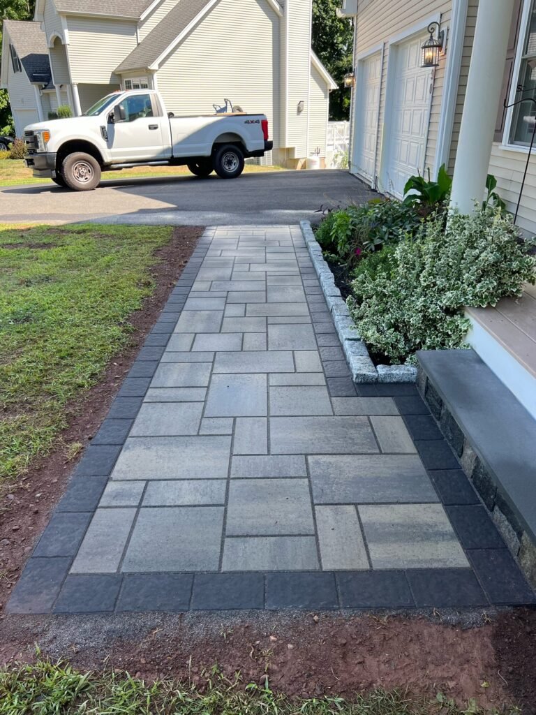 Paver walkway with a dark border along the side of a house in Middletown, CT