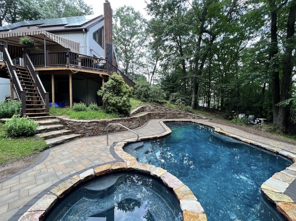 Pool patio with natural stone coping and a rebuilt stone wall in Southington, CT