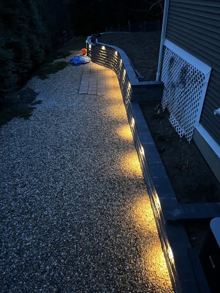 Landscape Lighting Retaining wall lighting along a side yard path at night in Southington, CT