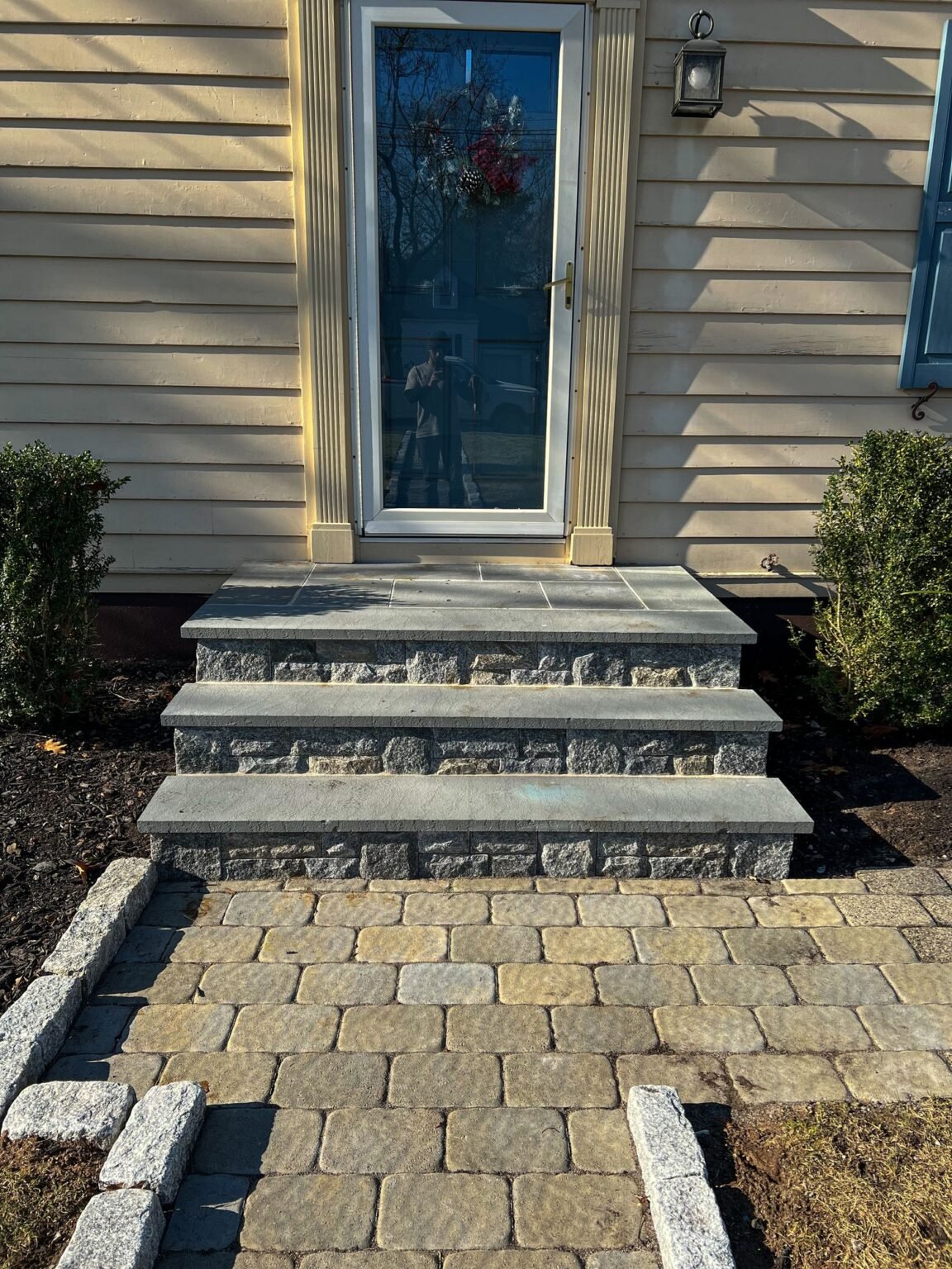 Stone veneer front steps with bluestone treads and a paver landing